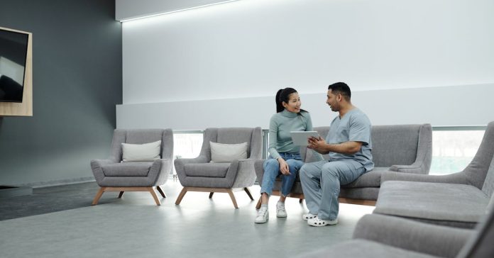 Uma mulher e um profissional de saúde conversam em uma sala de espera moderna.