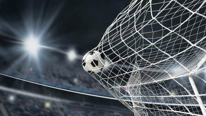 Uma bola de futebol entrando na rede de um gol em um estádio