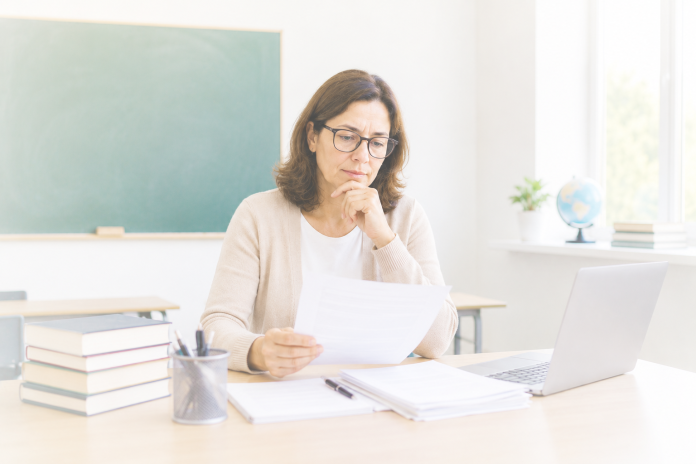 Professora da rede pública analisando documentos previdenciários em sala de aula organizada, representando a aposentadoria especial do professor servidor público, os critérios para concessão do benefício e o planejamento previdenciário conforme a legislação vigente.